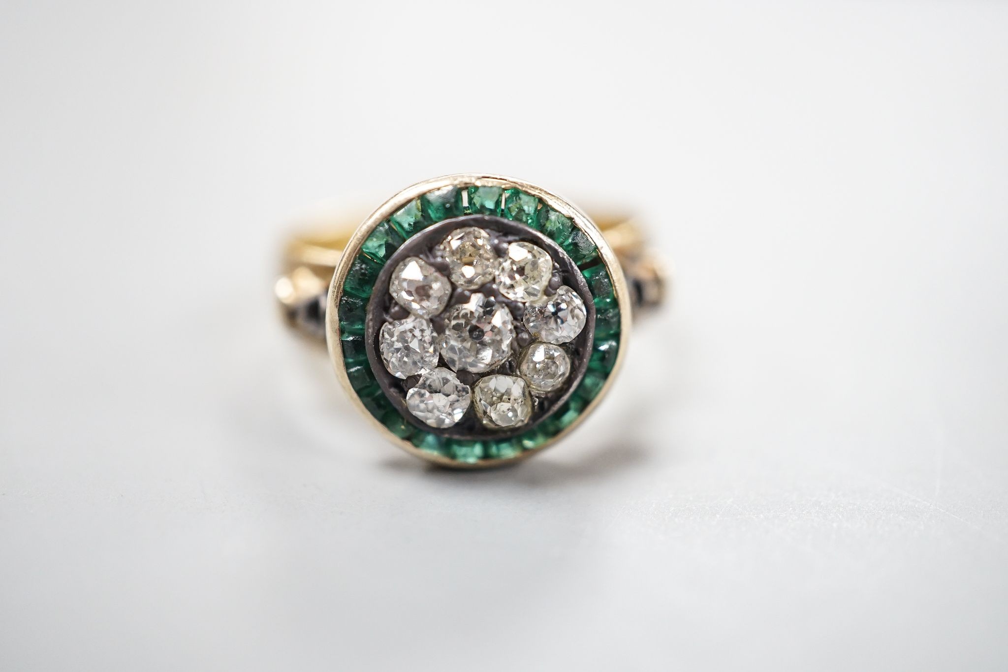 A George V 22ct gold emerald? and diamond set circular cluster ring, the shank with engraved inscription, size N/O, gross weight 5.3 grams.